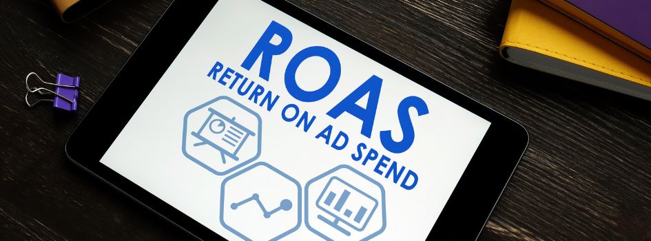 Οθόνη tablet με τον όρο ROAS (Return On Ad Spend) και εικονίδια αναλυτικών στοιχείων για τις στρατηγικές Smart Bidding στο Google Ads.