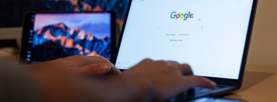 Χρήστης που πληκτρολογεί σε φορητό υπολογιστή στην αρχική σελίδα αναζήτησης της Google.